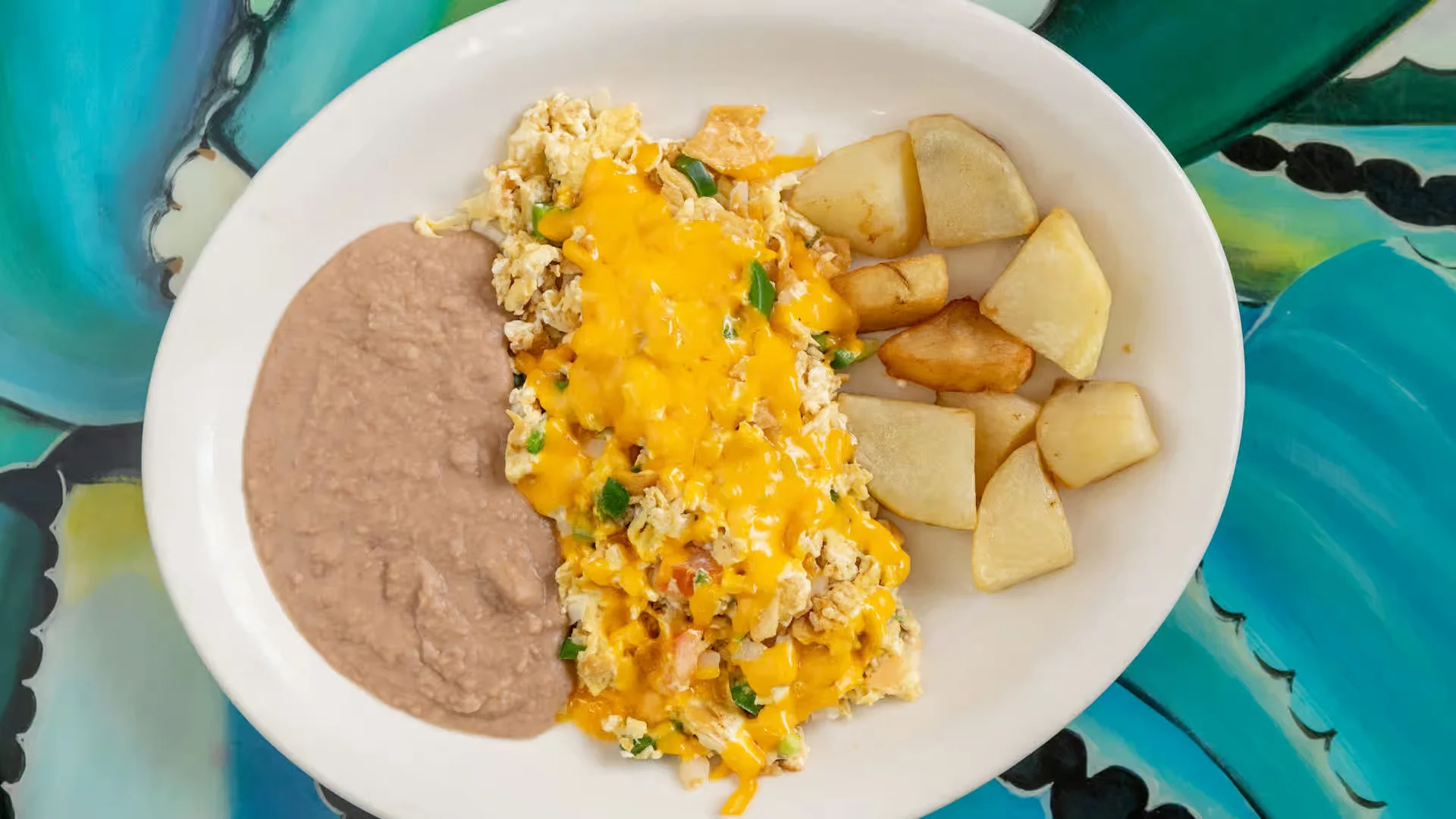 Migas Plate - A South Austin classic — scrambled eggs with crispy tortilla strips, jalapeños, tomatoes, and onions. Served with beans and tortillas.